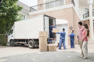 Young couple watching movers move boxes from the moving van