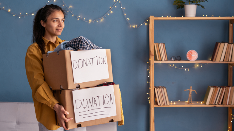 Woman holding boxes with clothing. Clothes donation or recycling
